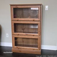 Full frontal view of the 3-shelf barrister bookcase showing oak wood finish and glass drop-down doors with wooden knobs.