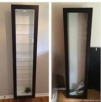 Two views of one Bertby wall display cabinet showing black/brown frame, glass door, and glass shelves inside.
