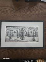 Frontal view of the framed artwork showing a forest with pine trees, mountains, and a sun/moon, in monochrome with simple brush or etching strokes.