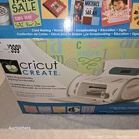 Box of Cricut Create cutting machine with price tag and craft project examples on box.