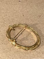 Oval gold brooch frame lying flat showing back view and overall shape