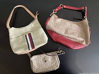 Overview of the three handbags together on black background showing logo fabric and colored leather-look accents