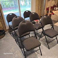 Six folding chairs with dark upholstered seats and backs, arranged in two rows in a basement room near a window.