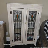 Front view of wooden bookcase with stained glass panel doors, showing rustic finish and metal hinges.