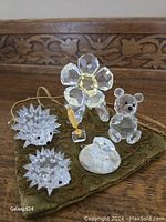 Photo showing all five crystal figurines on green cloth with carved wooden background.