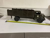 Side view of the military toy truck showing its length about 16 inches and open cargo bed with rear flap down.