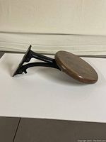 Side view showing the stool folded down with wooden seat and metal bracket.