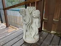 Front and side view of the cement plant stand with cherubs on a wooden deck.