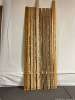 Ten vintage wood advertising yardsticks arranged side by side showing entire length with measurement markings and advertising text.