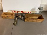 Overall view of the lot showing the Toast Master sign, two wooden boxes, twine dispenser, thermometer, and mason jar
