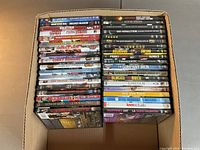 Box of 37 assorted DVDs arranged in two stacks, showing various movie titles across multiple genres.