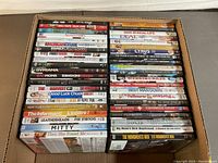 Photo of 42 DVDs stacked in two rows within a cardboard box, showing various movie titles on the spines.