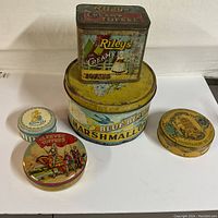 Overview of all five tins arranged on white surface