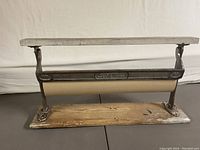 Front view of vintage EB Eddy paper dispenser showing metal frame and wooden base with paper roll in place.