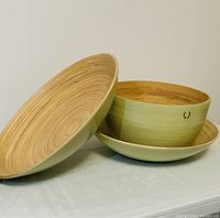 Three bamboo bowls stacked on light surface showing natural interior grain and light green exterior with Alfred Sung logo