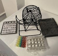 Family Bingo game components laid out including metal cage, bingo balls, colored markers, and cards