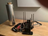 Photo showing the roll of aluminum foil standing upright next to unassembled mitre box parts including saw frame, rods, and plastic pieces scattered on a surface.