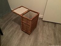 Open view of rectangular wicker hamper showing hinged lid with inset panels.