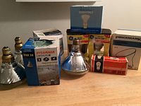 Photo showing various light bulbs including Sylvania Capsylite IR, Malden Outdoor Floodlight, GE soft white floodlight bulbs and a box of auto lamp bulbs.
