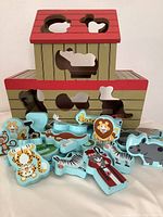 Front view of the Melissa & Doug Noah's Ark wooden animal shape sorter puzzle with animal pieces displayed outside the puzzle base, showing animals such as zebra, lion, giraffe, hippo, and more.