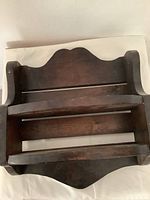 Front and angled view showing two-tier wooden trinket shelf with horizontal support bars and scalloped top edge.