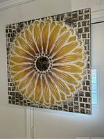 Front view showing large yellow daisy on square metal mosaic background hung on door.