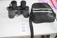 Full view of the black Magnivox binoculars alongside their black carrying case with shoulder strap and grey stripes.