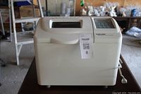 Full front view of the bread maker showing white color, top lid, and attached power cord.