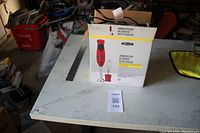Photo showing Bell+ Howell immersion blender with whisk in original box placed on a table in garage setting.