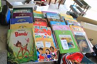 Image showing a collection of children's books arranged on a table including Disney storybooks and educational titles.