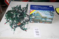 Photo of 100 count curtain string lights with clear bulbs on green wire and original box showing packaging.