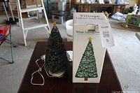 Christmas tree figurine with LED lights next to its box on a table