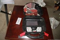 Open carrying case on table showing multiple sandpaper sheets of various colors inside.