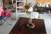 Adjustable desk lamp approximately 20 inches high with metallic dome-shaped shade and adjustable arm, shown on wood table.