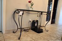 Full view of the hall table showing curved wrought iron legs, glass top, and decorative details.