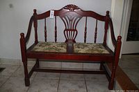 Full side angle view of the wooden hall seat showing carved details, armrests, and floral seat cushions.