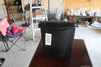 Front view of a black paper shredder showing its compact design and sticker label.