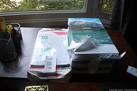 Two packages of print/copy paper on a wooden desk by a window, one Xerox Business 4200 and one Earth Choice office paper.