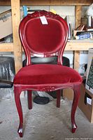 Front view of red wooden chair with upholstered velvet seat and backrest showing carved details and curved legs.
