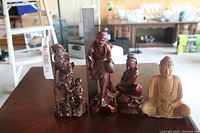 Four root sculptures displayed on table showing varying heights and details including a ruler for scale.