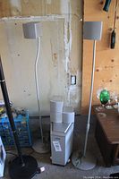 Full view of Sony speakers, subwoofer, and surround sound speakers against a wall with wooden panel background.