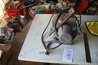 Electric circular saw placed on a table with manual visible alongside power cord, surrounded by other household items.