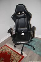 Front view of black Vitesse gaming chair with ergonomic design, padded armrests, headrest pillow, and lumbar cushion.