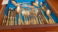 Full set of flatware in blue felt roll showing knives, forks, spoons and serving pieces