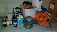 Wide shot showing propane stove box, lanterns, propane bottles, sleeping bags and life jacket