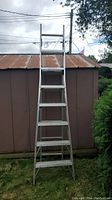Full front view of the aluminum extension ladder in its extended height against an outdoor shed.