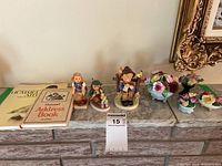 Overall setup showing figurines lined up with art books and china floral baskets on marble surface.