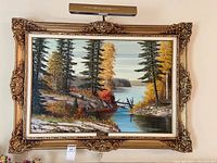Full view of the framed landscape painting with art light mounted above.