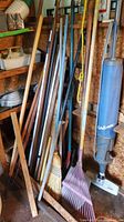 Collection of garden poles and broom leaning against wall in shed
