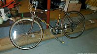 Full side view of vintage brown 10-speed bicycle with visible wear, resting on a basement floor